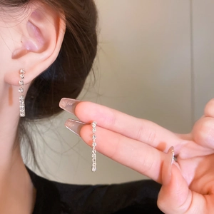 Close-up of sparkling rhinestone tassel earrings on model and hand display