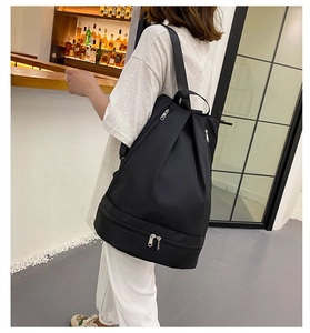 Rear view of model wearing a black waterproof Oxford cloth backpack with separate bottom compartment