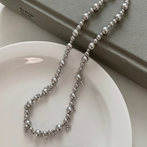 Elegant vintage faux pearl necklace with silver cross charms in a ceramic bowl