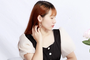 Close-up of golden hollow heart drop earrings worn by a model for a stylish look