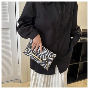 Detail of zebra pattern envelope clutch with gold V-shape metal trim and leather texture