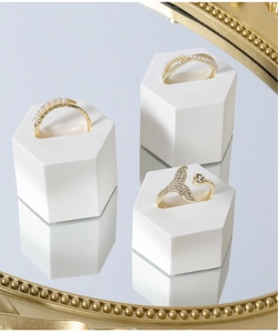 Detailed view of gold rings with pearls and fishtail design on hexagonal stands