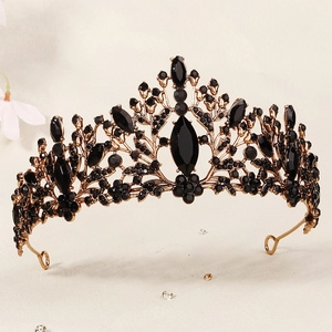 Detail of vintage black and gold tiara with marquise crystals on a textured background