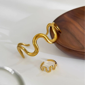 Polished gold wavy metal jewelry set with minimalist open bangle and matching ring