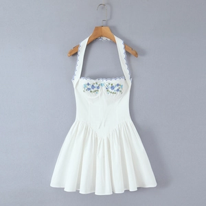 Detail of blue floral embroidery and scalloped trim on white halter neck mini dress
