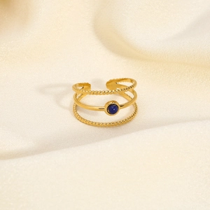 Detail of 18K gold plated multi-layer stainless steel ring with a blue gemstone bead