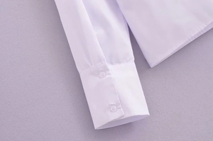 Détail de la manchette d'un chemisier blanc avec deux boutons blancs polis