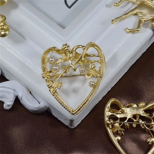 Vintage matte gold heart brooch featuring a cupid angel and pearls on a satin background