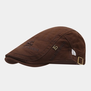 Close-up of vintage brown cotton canvas newsboy cap with metal logo and embroidery