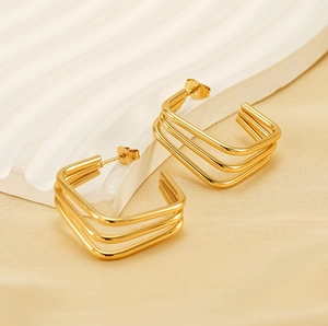Detail of 18K gold-plated triple-layer geometric earrings on luxury silk and ceramic