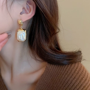 Detail of vintage French style gold earrings with textured metal and square faux pearl