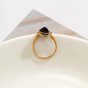 Detail of handmade gold wire-wrapped ring featuring a raw black stone in boho style