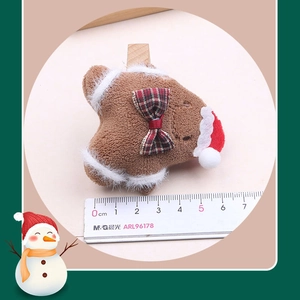 Detail of plush gingerbread man Christmas ornament with red bow and santa hat accessory