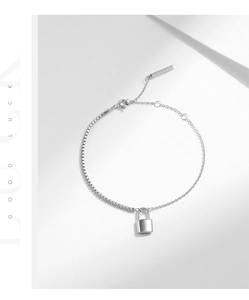 Detailed macro view of silver chain bracelet with polished padlock charm and logo tag
