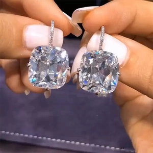 Macro shot of cushion-cut zircon earrings with pave-set stones on silver-tone hooks