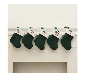 Série de cinq chaussettes de Noël en tricot vert foncé avec lettres brodées sur cheminée