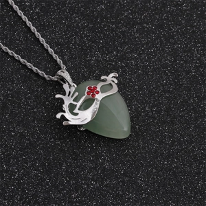Détail du pendentif masque en aventurine verte avec gemmes rouges sur chaîne torsadée