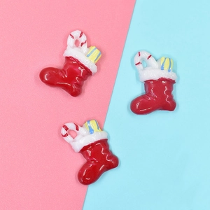 Close-up of three red resin Christmas stocking charms with candy canes and gift boxes