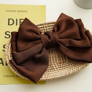 Close-up of triple-layered brown satin bow hair clip with elegant silk-like texture