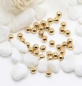Vue macro de perles dorées rondes sur des galets blancs pour création de bijoux