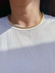 Detail showing high-quality gold braided mesh necklace texture on model in natural light
