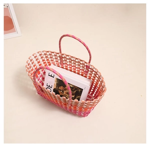 Top view of colorful woven straw tote bag with round handles on a clean beige surface