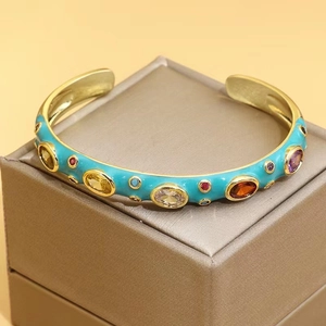 Detailed shot of sky blue enamel gold cuff bracelet with colorful inlaid gemstones