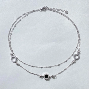 Macro detail of silver double-layer necklace with black Roman numeral hollow pendants