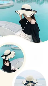 Close-up of woven straw sun hat featuring a black ribbon bow and elegant wavy brim