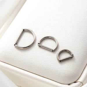 Three pieces of G23 titanium D-ring nose hoops and hinged ear cuffs in silver finish