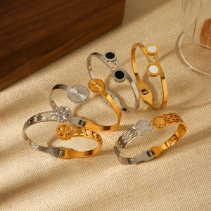 Flat lay of mixed gold and silver stainless steel bangles with star and Roman patterns