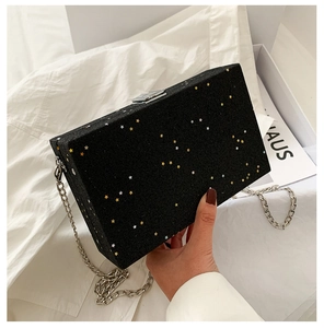 Detail of black rectangular evening bag featuring glitter texture and silver star patterns