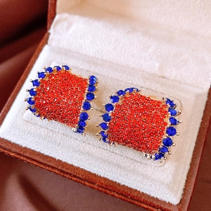 Detail view of vintage C-shaped earrings with red and blue crystals in a jewelry box