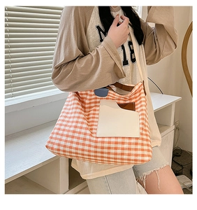 Detail of orange checkered canvas tote bag with white front pocket and brown straps