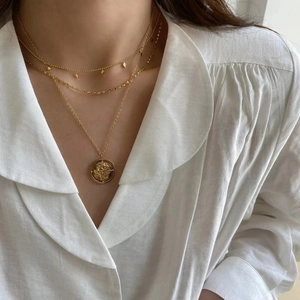 Detail of 18K gold-plated double-layer necklace with rose pendant on white shirt
