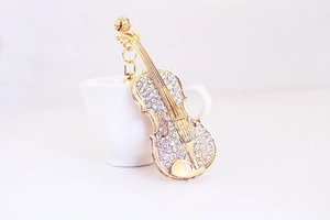 Gros plan d'un porte-clés violon doré avec strass étincelants posé sur une tasse