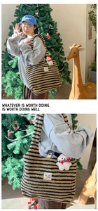 Detail of striped plush tote bag with fuzzy dog charm and decorative woven label