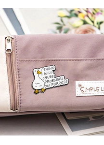 Cartoon duck enamel pin with funny quote on a purple canvas bag detail shot