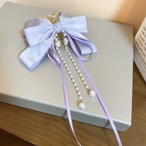 Detail of light purple ribbon hair claw with elegant pearl tassels and long streamers