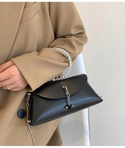 Detail view of black handbag with rhinestone ring handle and silver metal chain decoration