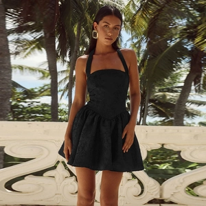 Detail of black halter mini dress featuring textured jacquard fabric in a tropical resort setting
