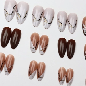 Brown long almond press-on nails with minimalist leaf patterns and silver glitter accents
