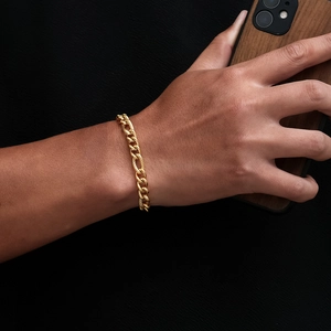 Close-up of a high-shine gold-plated Cuban chain bracelet worn on a wrist