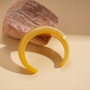 Artistic close-up of amber resin open bangle cuff on textured stone element
