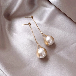 Detail of elegant gold drop earrings with pearls and crystals on champagne silk background