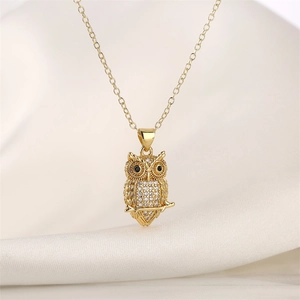 Detailed close-up of a gold owl pendant with colorful zircons on soft silk fabric