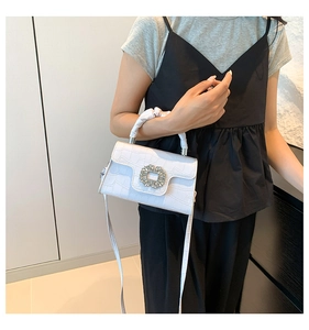 Détail du sac à main blanc motif crocodile avec boucle en cristal sur le mannequin