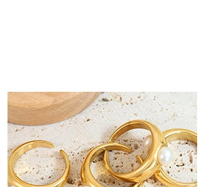 Detailed view of gold rings with pearls on a rustic stone background with wooden tray