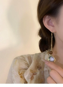 Close-up of vintage long tassel earrings with wood bead and iridescent shell pendant on model