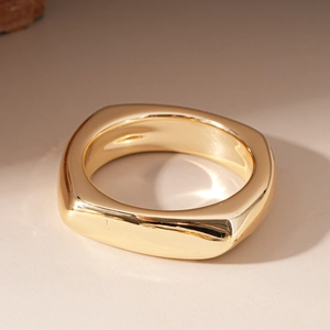 Close-up of a minimalist chunky square ring with a polished golden metallic finish